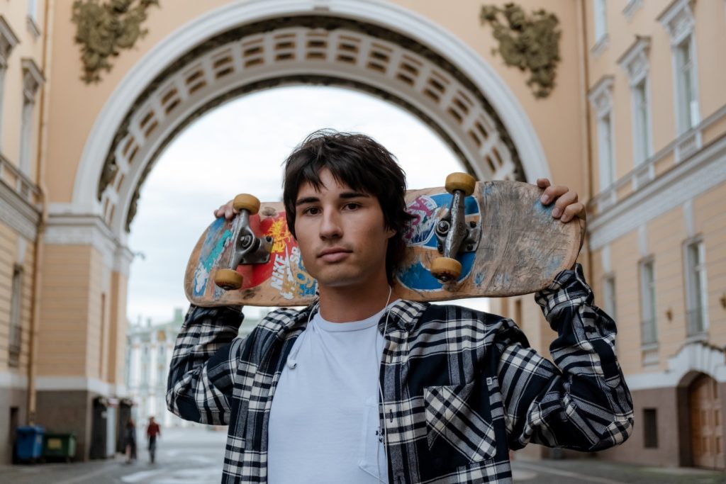 Ragazzo con camicia a quadri bianca e nera che tiene in mano un peluche blu e arancione